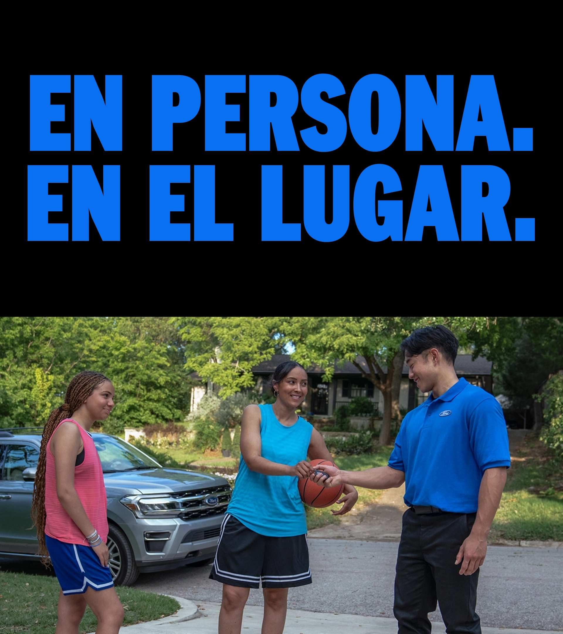 Dos jóvenes de pie en la entrada de una casa hablando con un técnico de servicio Ford