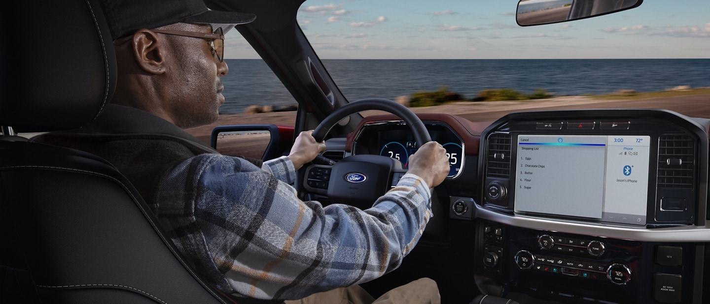 Una persona al volante conduciendo una Ford F150® 2022 con el océano de fondo
