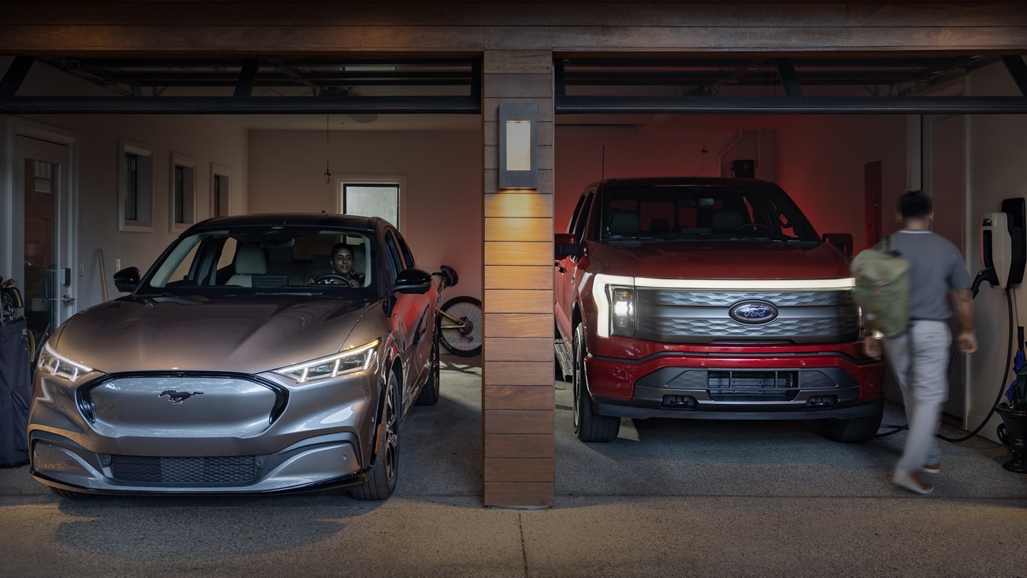 Un Ford Mustang Mach-E 2023 y una Ford F-150 Lightning 2023 estacionados uno al lado de otro en un garaje residencial