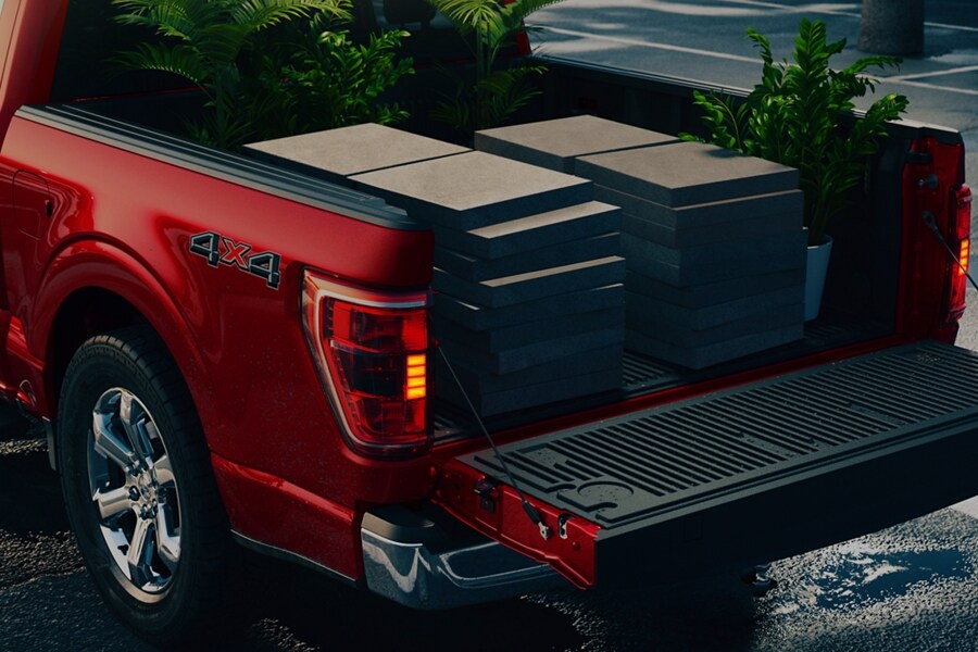 Vista de la puerta trasera plegada de una F-150® y adoquines de concreto grande para patio en la plataforma de la camioneta