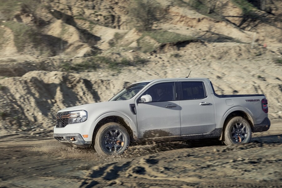 Una Ford Maverick® Tremor® 2023 levantando polvo mientras circula en un terreno desértico arenoso