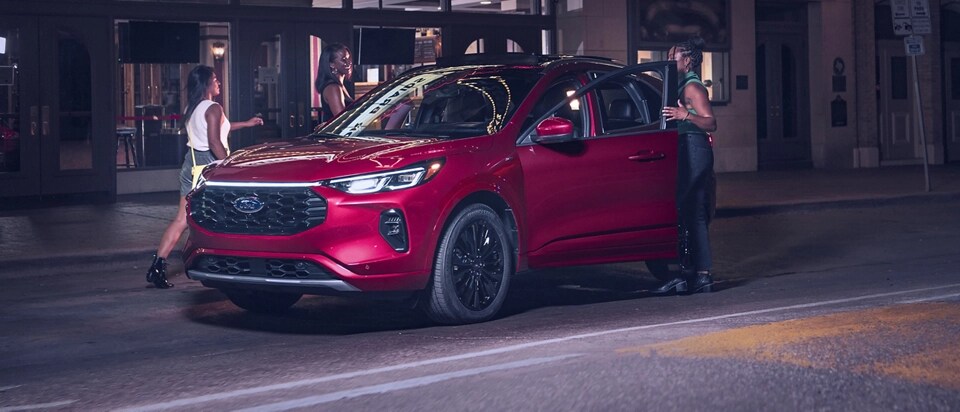 Un grupo de amigos sube a una SUV Ford Escape® 2025 Red de noche