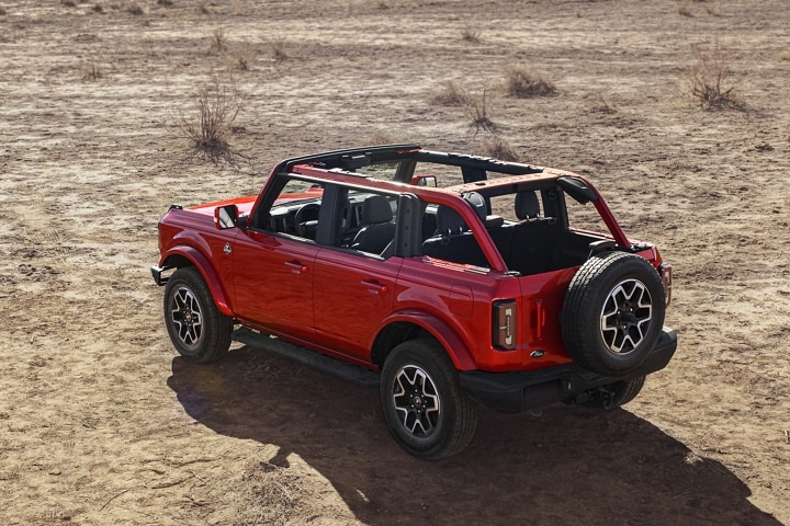 Una Ford Bronco® Outer Banks® 2024 de cuatro puertas en Hot Pepper Red estacionada en el desierto sin techo ni puertas