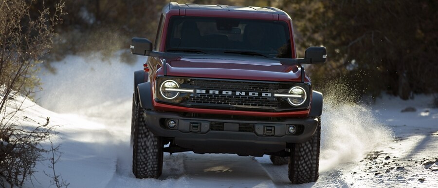 Una Ford Bronco® Wildtrak® 2024 andando por terreno escabroso en un sendero cubierto de nieve