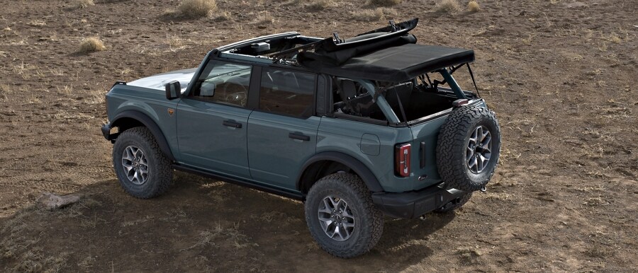 Se muestra el modelo Ford Bronco® Badlands® 2024 de cuatro puertas en Azure Gray con el techo blando abierto por la mitad y sin el panel trasero
