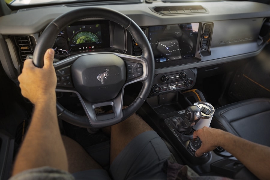 Interior de una Ford Bronco® 2024 mientras el conductor cambia los equipos, y nosotros vemos el tablero