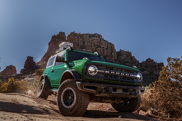 Una Ford Bronco® Black Diamond™ 2024 de dos puertas en Eruption Green circulando por un terreno desértico