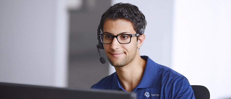 Hombre usando un auricular con micrófono sentado enfrente de la pantalla de una computadora
