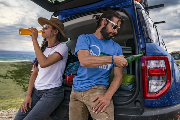 Dos personas paradas en la parte trasera de una SUV Ford Bronco® Sport 2023 usando el destapador integrado
