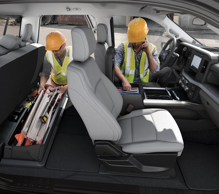 Dos hombres con casco accediendo a las áreas de almacenamiento de la cabina de la Ford Super Duty® Chassis Cab 2024