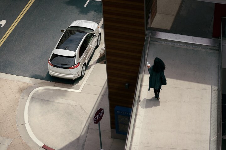 Una mujer en una pasarela peatonal mirando su SUV Ford Edge® 2023 estacionada en la calle abajo