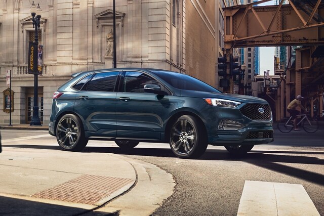 Una SUV Ford Edge® ST 2024 en Stone Blue doblando en una esquina en una ciudad