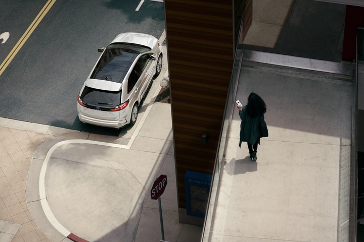 Una mujer en una pasarela peatonal mirando su SUV Ford Edge® 2024 estacionada en la calle abajo