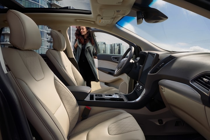 Interior del modelo Ford Edge® Titanium 2024 con una mujer cerrando la puerta del lado del conductor