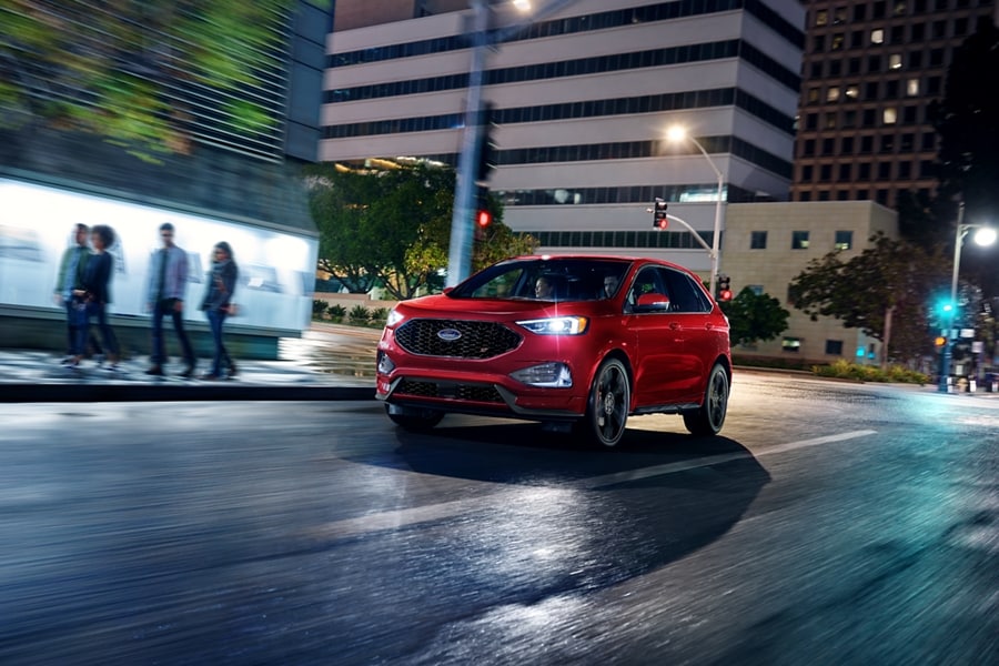 Una SUV Ford Edge® 2024 en Rapid Red andando en una ciudad de noche