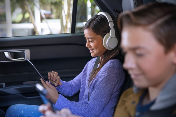 Dos niños usan tablets a través del Wi-Fi del vehículo en el asiento trasero de un Ford