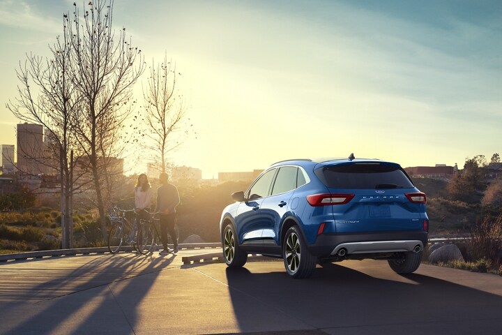 Una Ford Escape® 2023 en Atlas Blue estacionada con vistas al paisaje urbano al atardecer​​​​​​​