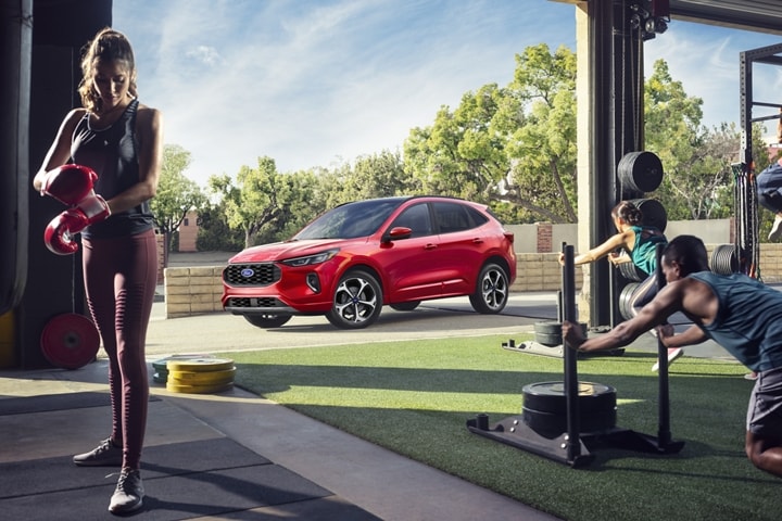 Una Ford Escape® 2023 en Rapid Red Metallic Tinted Clearcoat estacionada junto a un gimnasio al aire libre