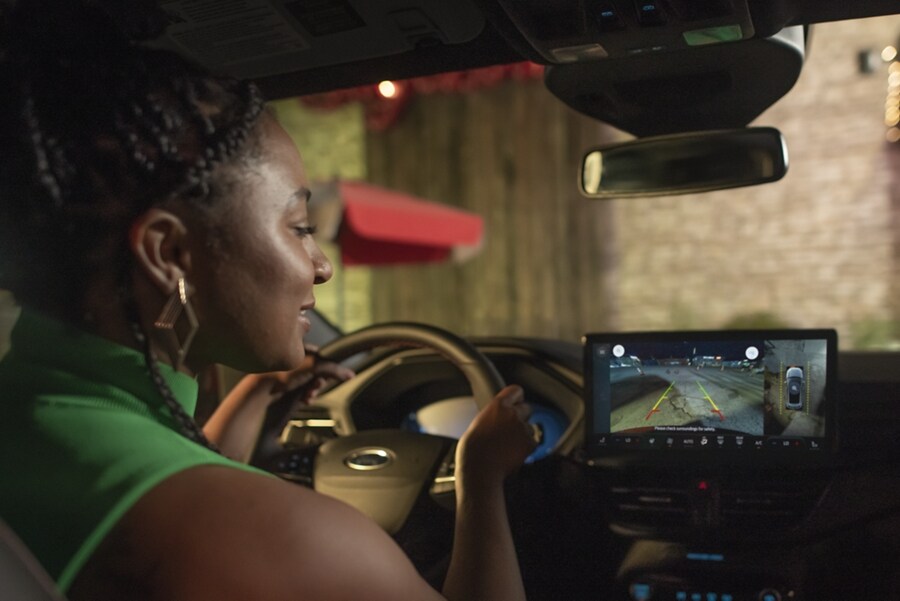 Primer plano del interior de una Ford Escape® 2023 mientras el conductor mira la imagen de la pantalla táctil al retroceder