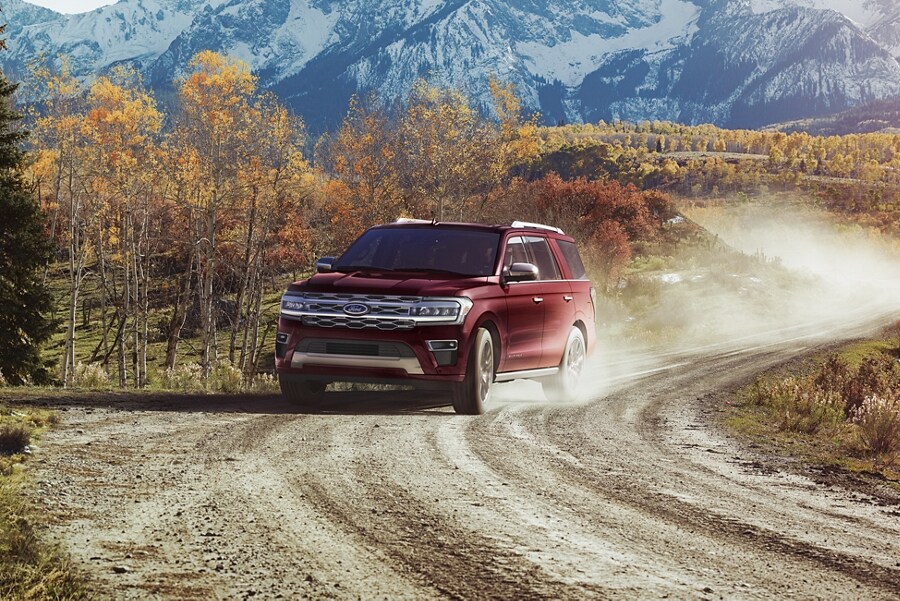Una Ford Expedition 2023 andando por un camino de tierra con montañas de fondo