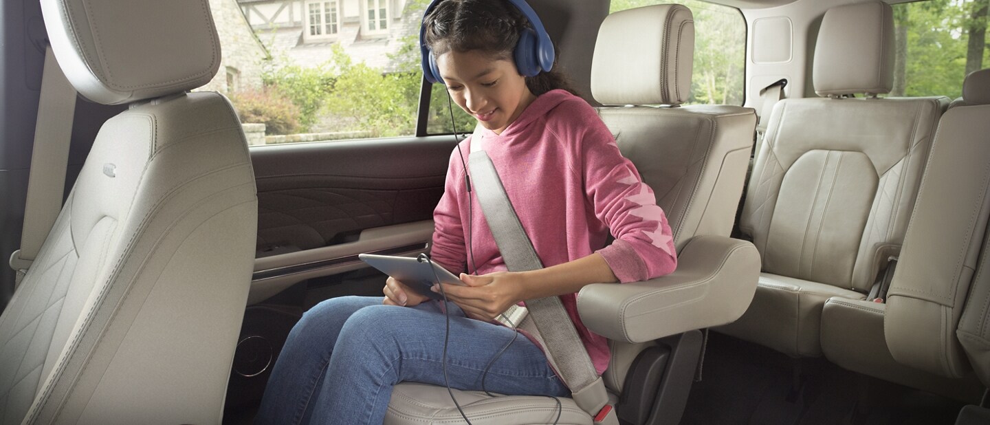 Una niña dentro de una ​​​​​​​SUV Ford Expedition 2024 usando su tablet inalámbrica conectada al hotspot Wi-Fi en el vehículo.