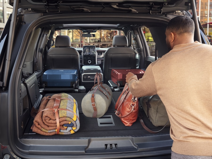 Un hombre carga bolsos y otros artículos en la cajuela de una Ford Expedition 2024
