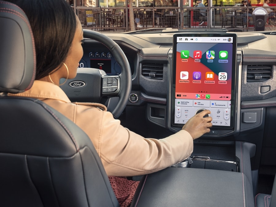 Primer plano de una mujer en el asiento del conductor de una SUV Ford Expedition 2024​​​​​​​ usando la pantalla táctil LCD central del vehículo