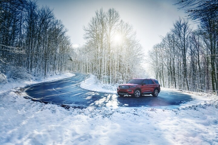 El modelo Ford Explorer® Platinum 2023 en Rapid Red Metallic Tinted Clearcoat circulando por una curva nevada