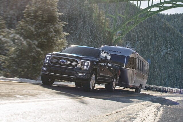 Una Ford F-150® 2023 remolcando una casa rodante cuesta arriba por un camino