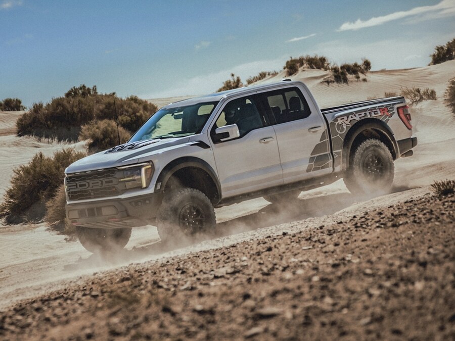 Una Ford F-150® Raptor 2024 andando en modo todo terreno por el desierto levantando polvo