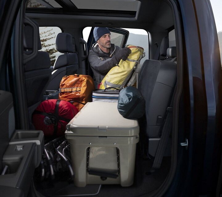 Interior de una Ford F-150® 2024 que muestra el piso de carga plano trasero con equipo para acampar