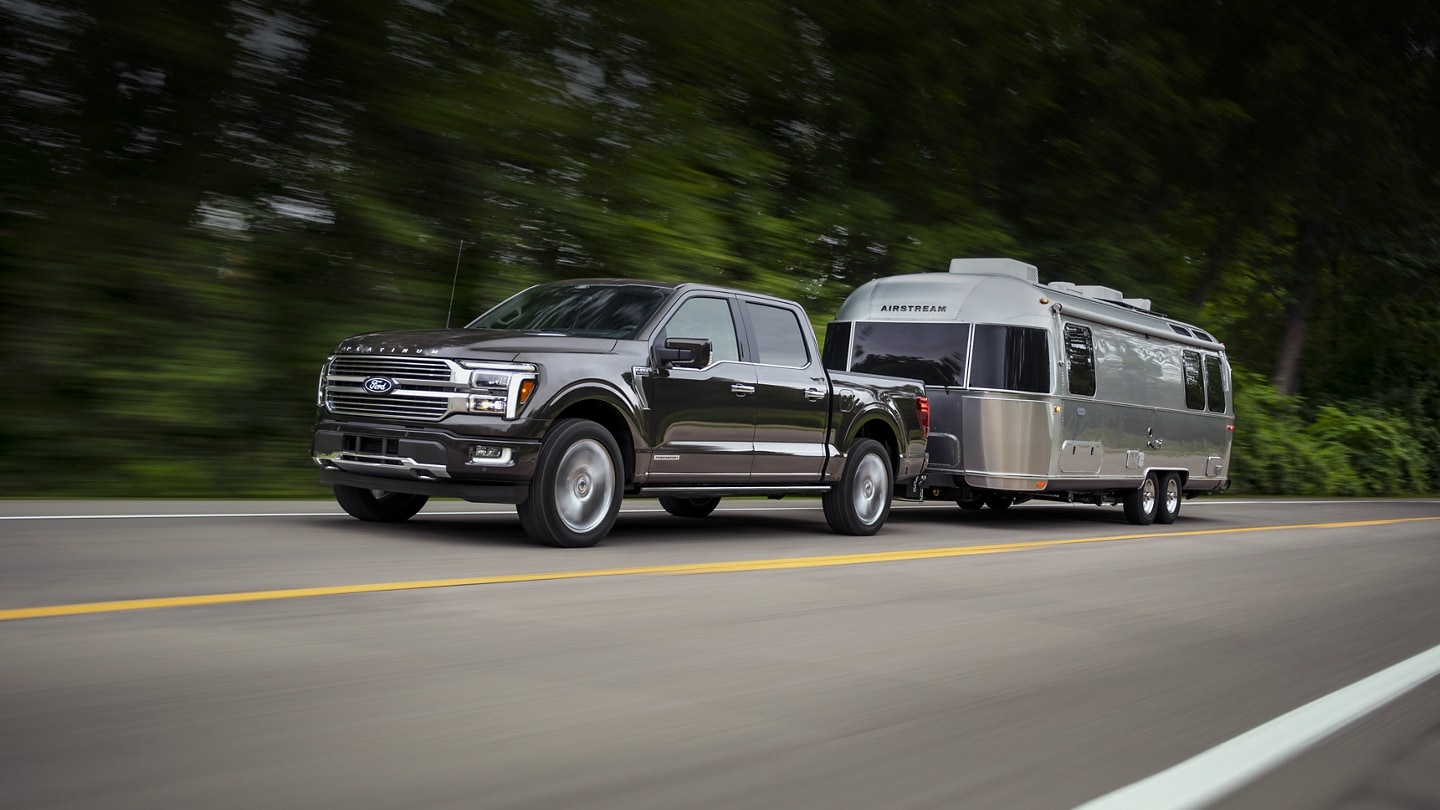 Una camioneta Ford F-150® Platinum® 2024 remolcando un tráiler con una caravana