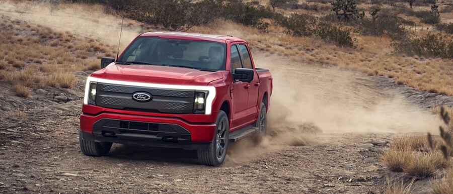 Una Ford F-150 Lightning® 2023 circulando agresivamente por un camino en el desierto levantando polvo