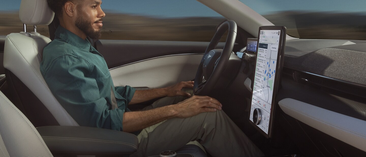 Hombre usando Ford BlueCruise sentado en el asiento del conductor de una Ford Mustang Mach-E® 2023 con las manos en las rodillas