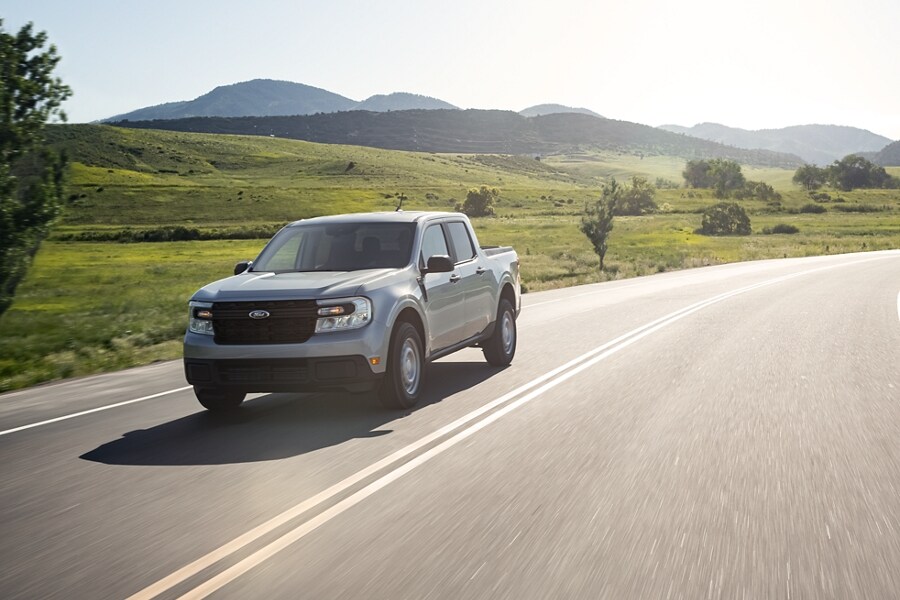 Una camioneta Ford Maverick® 2023 en una carretera rural con montañas en segundo plano