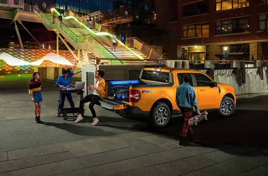 Dos personas y un DJ festejando con su Camioneta Ford Maverick® 2023” en Cyber Orange