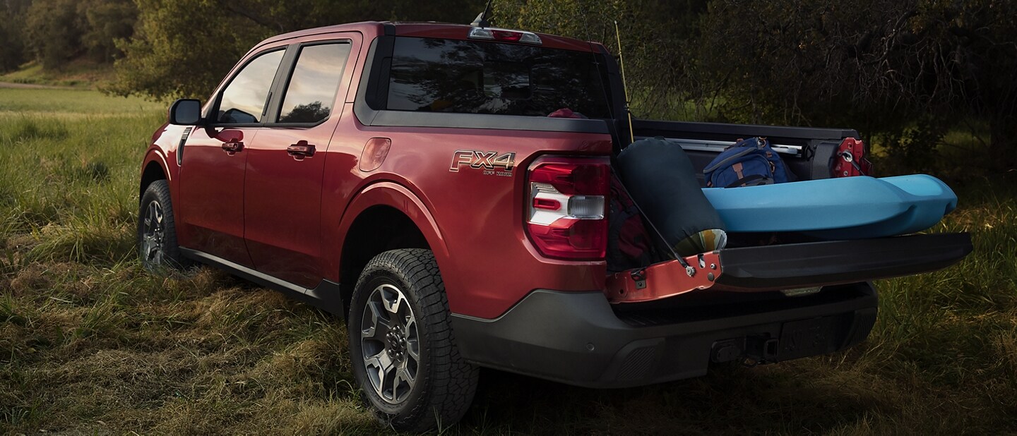 Una camioneta Ford Maverick® 2023 estacionada con la puerta trasera de múltiples posiciones abierta para guardar el equipo de campamento