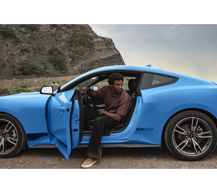 Una persona saliendo de un Ford Mustang® 2024 cupé estacionado en el desierto