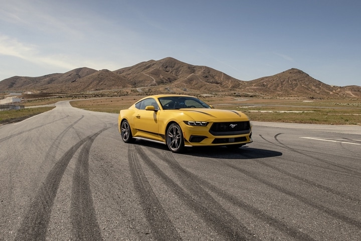 Una Ford Mustang® EcoBoost® cupé 2024 en Yellow Splash Metallic Tri-coat estacionada en una pista