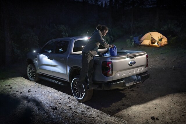 Una Ford Ranger® 2024 estacionada en un campamento de noche con la Iluminación de Zona encendida