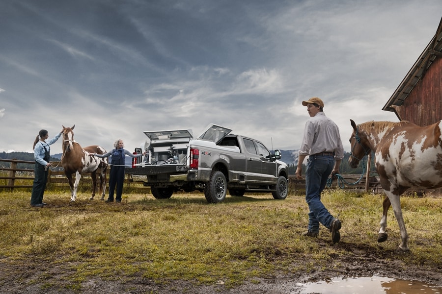 Dos mujeres de pie con un caballo cerca de una camioneta Ford Super Duty® F-250® Platinum 2024 con la puerta trasera baja