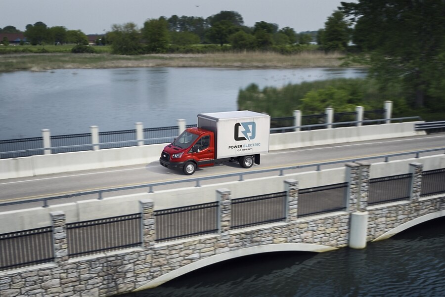 Ford Transit® Chassis Cab 2023 andando sobre un puente con un lago de fondo