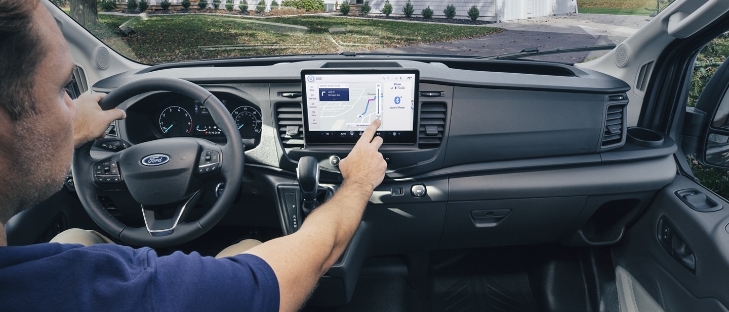 Interior de una van Ford Transit® 2023 con un conductor usando el sistema de navegación de la pantalla táctil