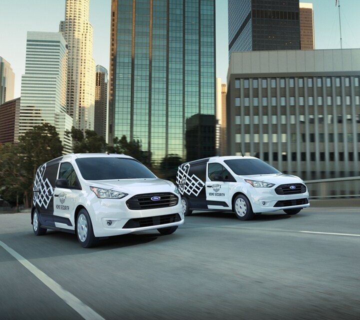Dos Ford Transit Connect Cargo Van 2023 con gráficos comerciales no originales andando por la carretera