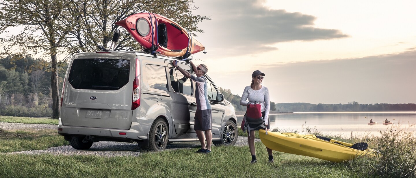 Wagon para Pasajeros Ford Transit Connect 2023 en Solar Silver al lado de un lago con dos personas que practican kayak