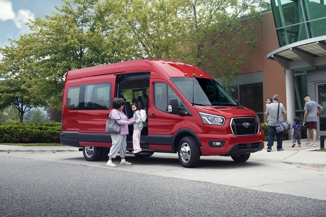 Una mujer ayudando a un niño afuera de una van Ford Transit® 2023